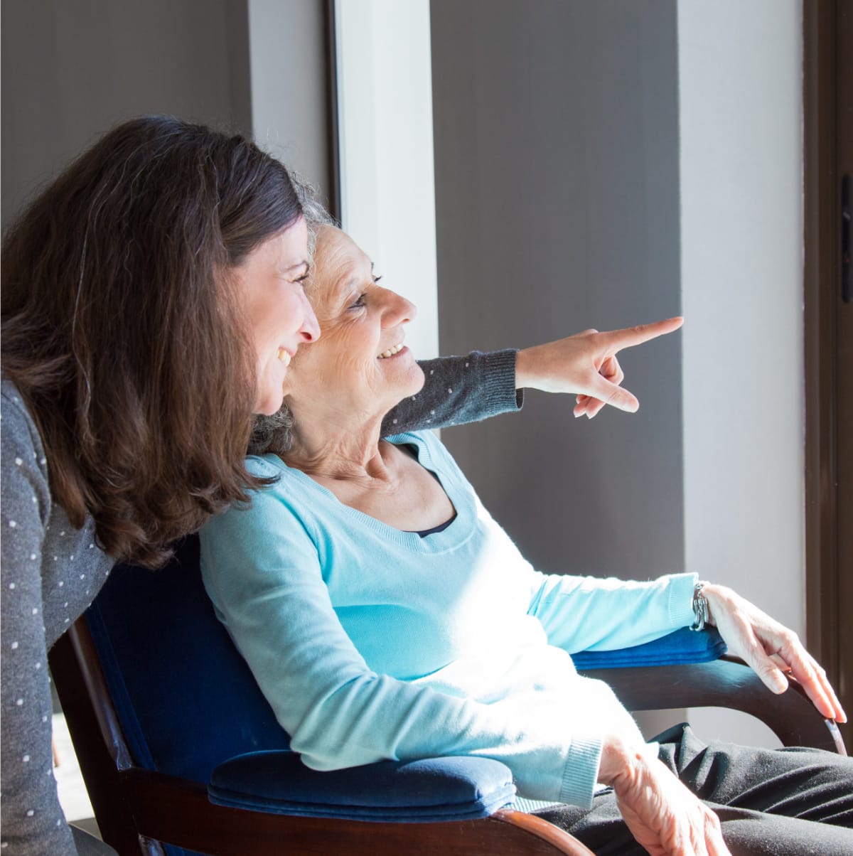 Older woman and her daughter sitting down and looking out a window