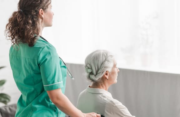 Caregiver pushing an older woman in a wheelchair